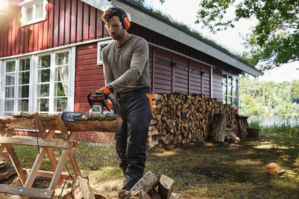 Petrol Chainsaw MS 182 Petrol chainsaw being held by man and chopping wood in forrest setting