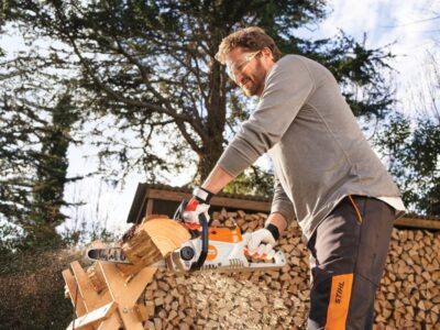 battery chainsaw being held by man cutting wood in a forrest